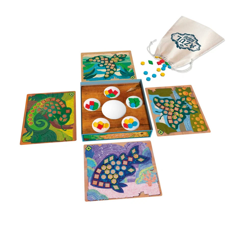 A colorful children's board game set displayed on a white background, including four illustrated game boards, an open central play box with round pieces, loose colored tokens, and a cream drawstring bag with a printed logo.