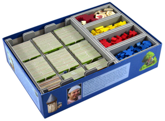 Board game box with compartments containing colorful pieces on a white background