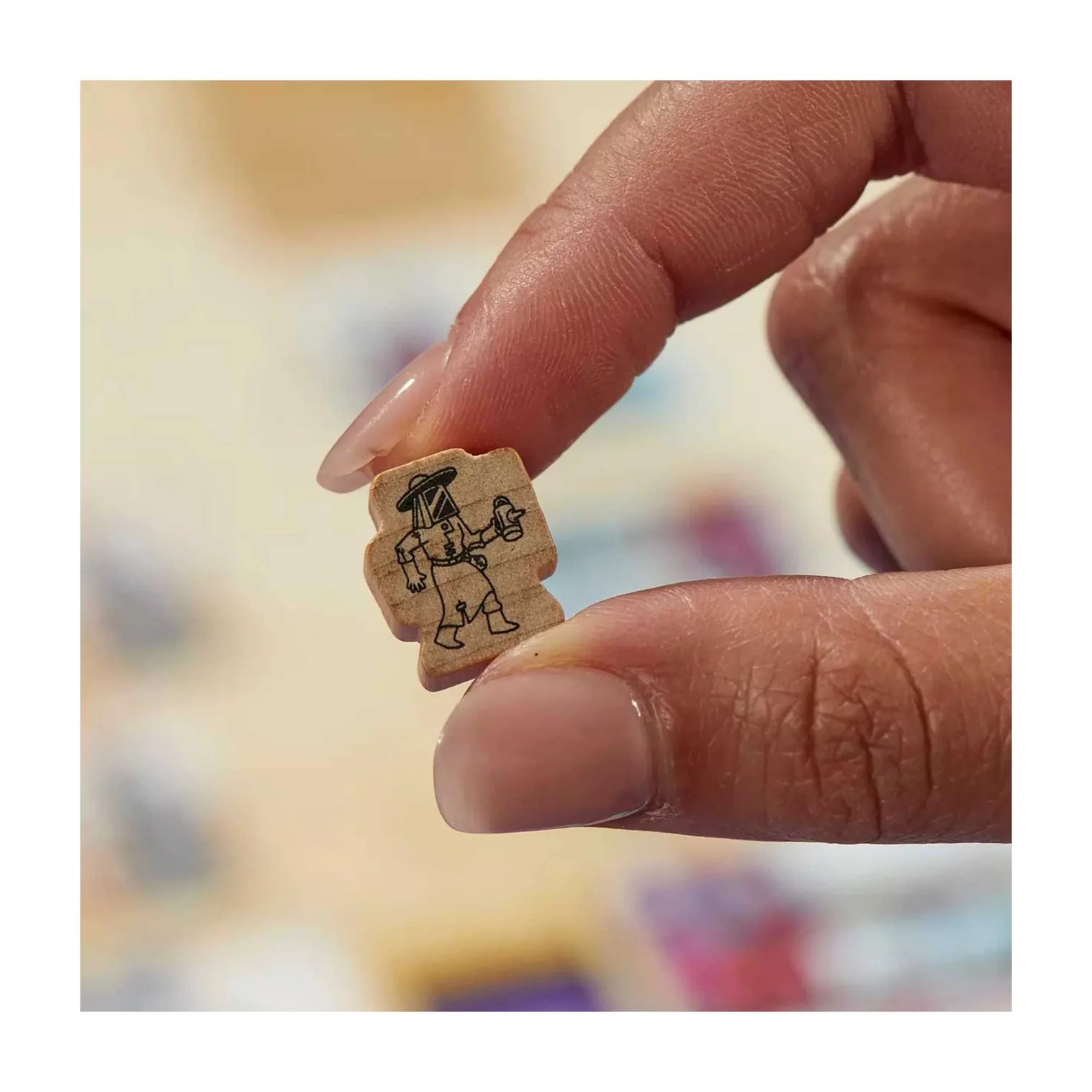 Hand holding a small wooden stamp with a design on a blurred background