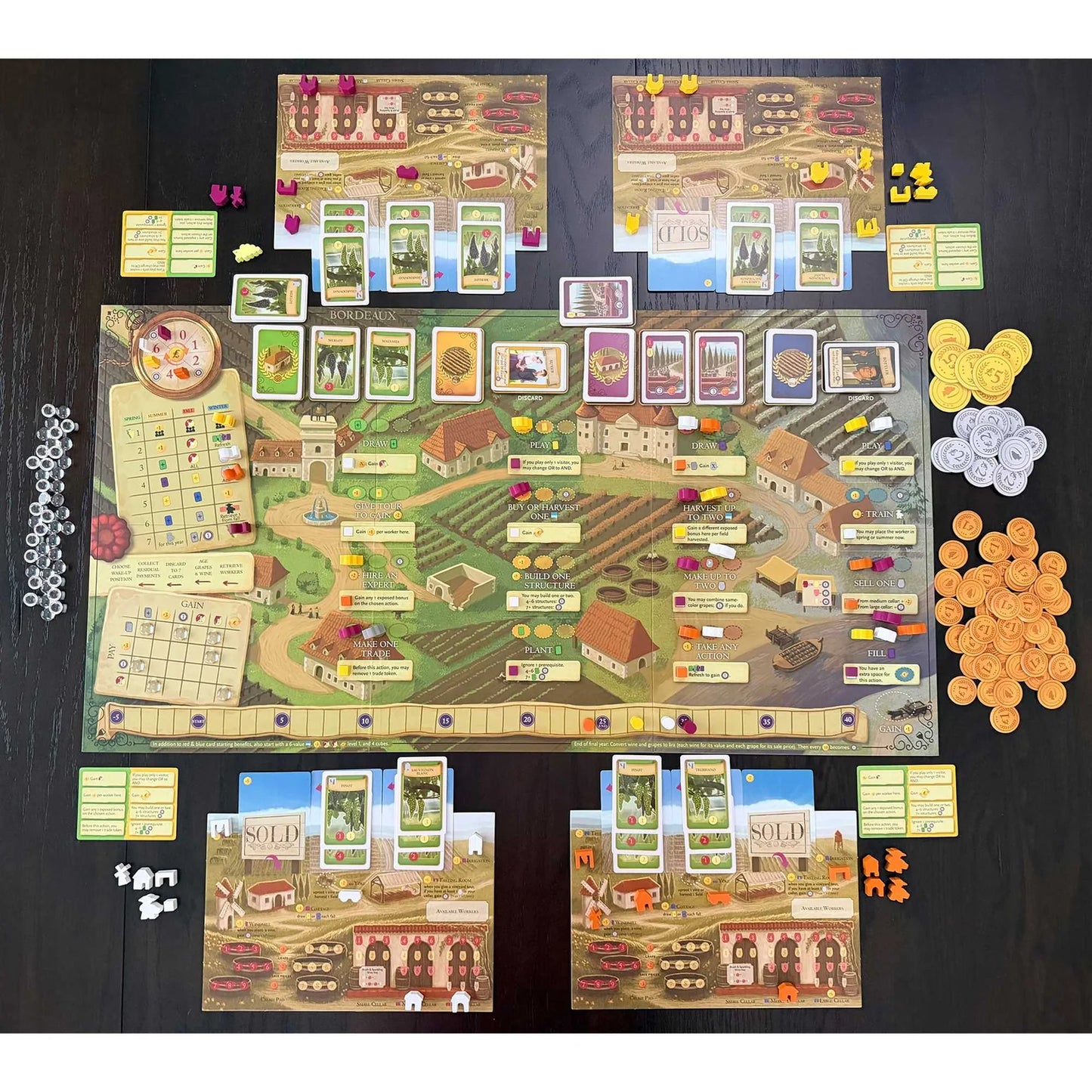 Board game setup with various components on a dark surface